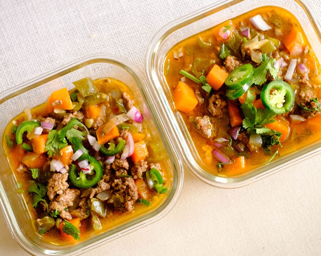 glass meal prep containers that have ground beef, sweet potatoes, green bell peppers, cilantro, jalapeno, and red onions