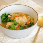 round bowl with chicken meatball soup, diced carrots, celery, onions, and baby kale