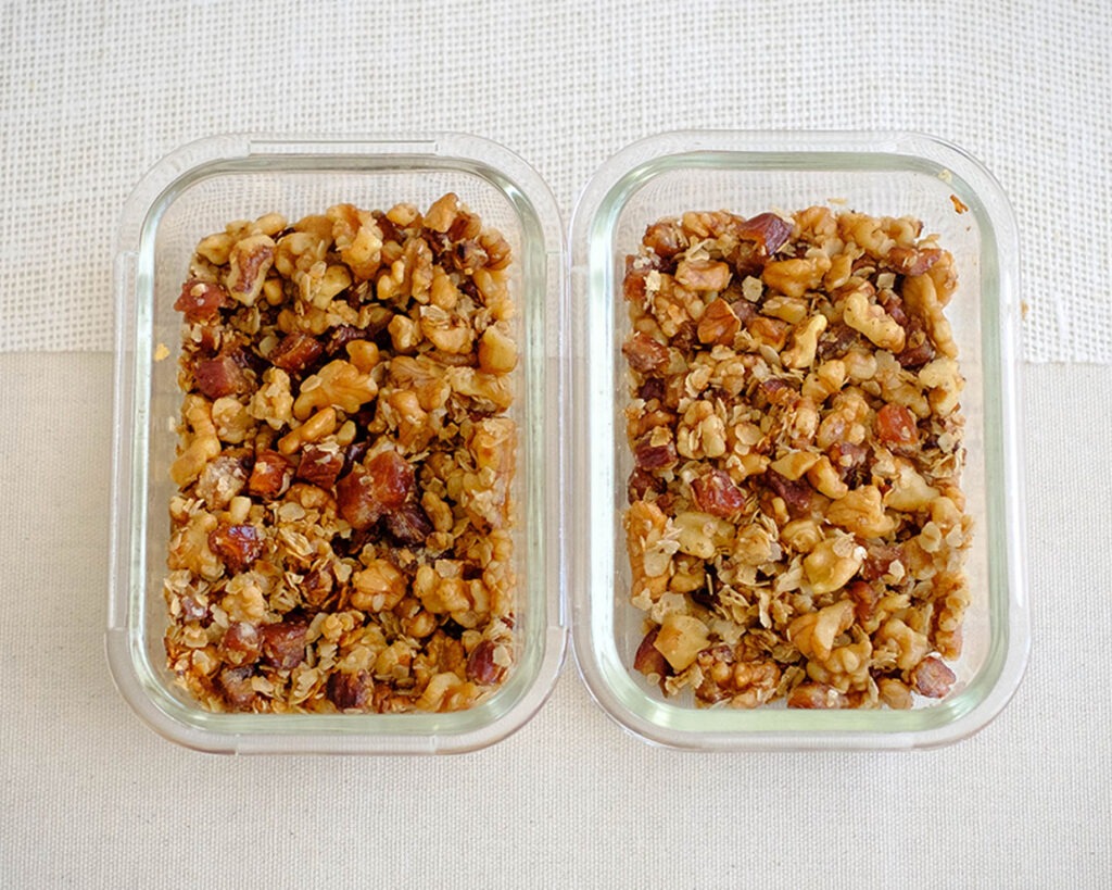 glass meal prep containers with a healthy breakfast of dates, rolled oats, and walnut granola