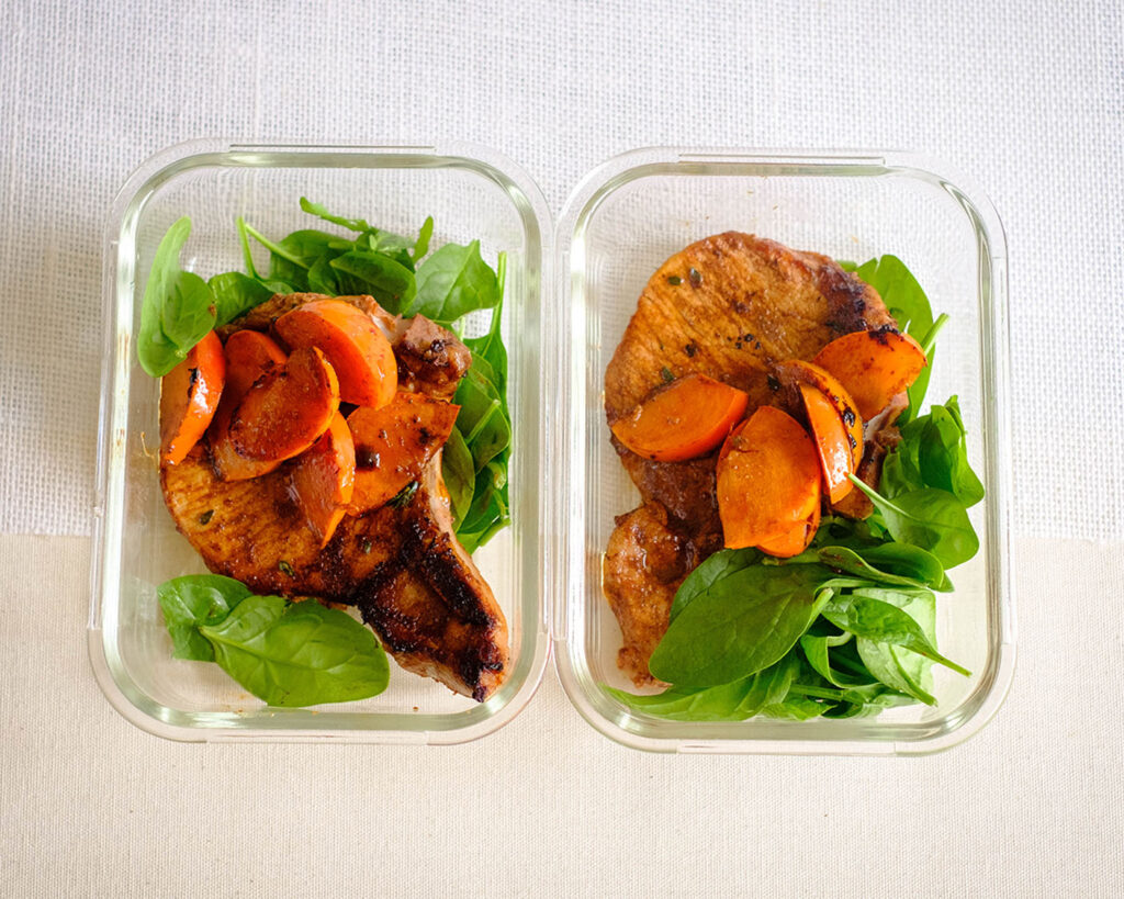 pork meal prep in containers with balsamic glazed porkchops with persimmons and baby spinach
