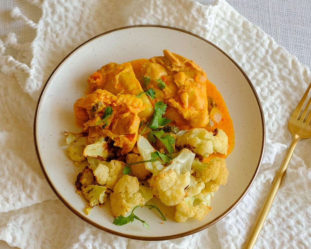 round plate with instant pot butter chicken and roasted cauliflower