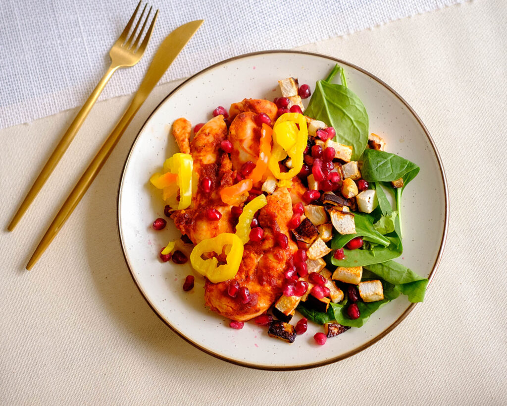 oven baked harissa chicken on a plate with veggies