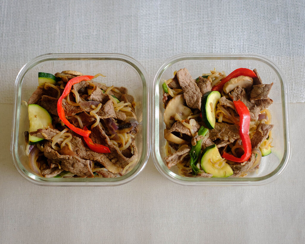 weekly meal prep glass square containers with sliced beef stir fry with bell peppers, sliced zucchini, and sliced mushrooms, and bean sprouts