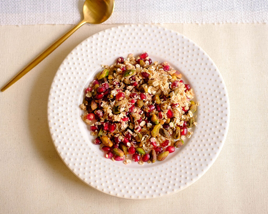 round plate with pistachios, pomegranate, and rolled oats