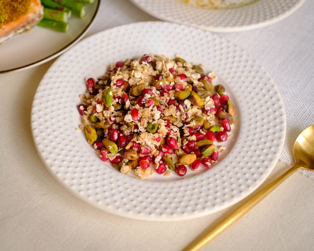 round plate with pistachios, pomegranate, and rolled oats