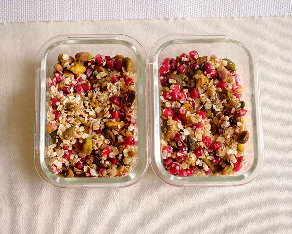 rectangular glass meal prep container with pistachios, pomegranate, and rolled oats