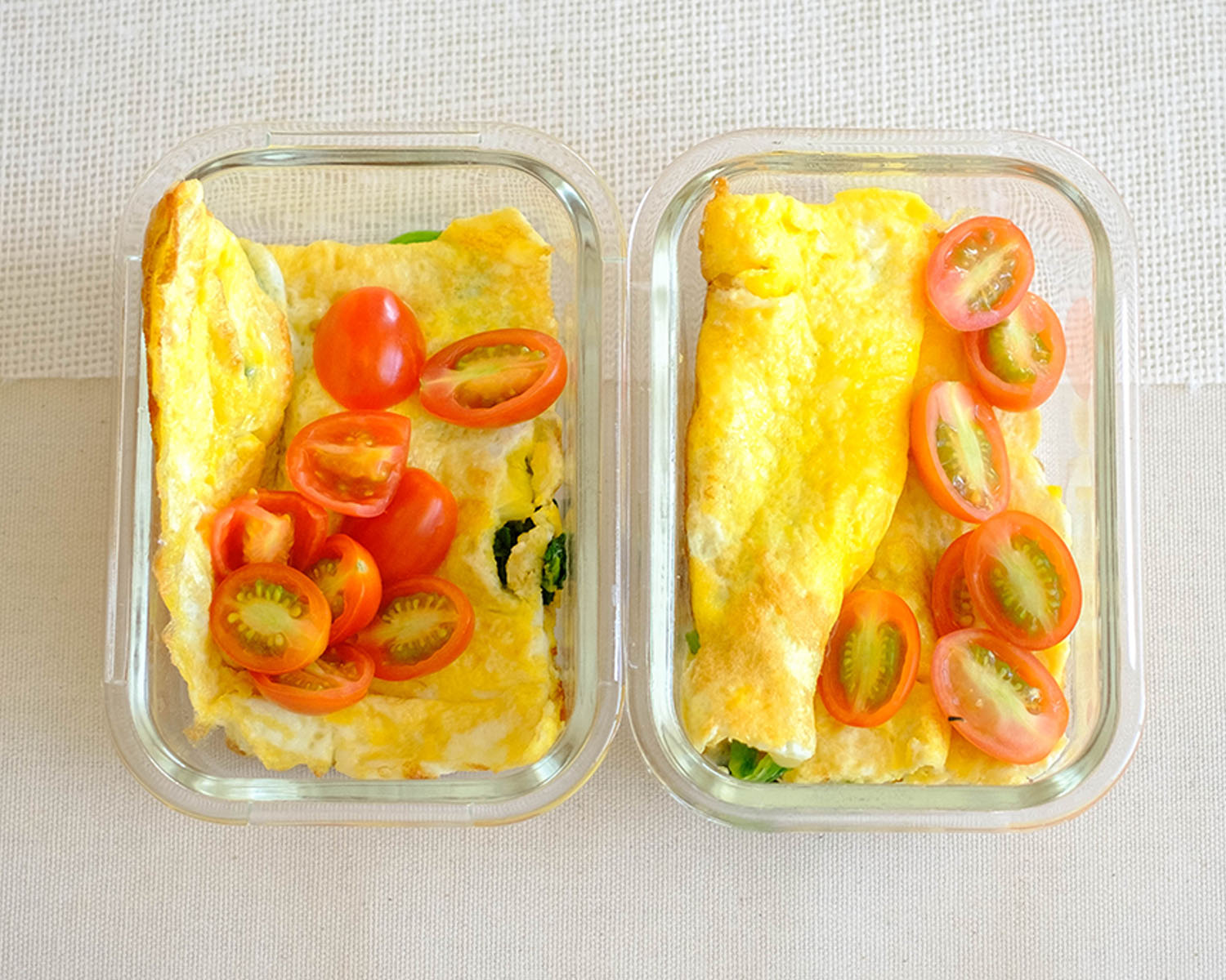 glass meal prep containers with omelette topped with eggs