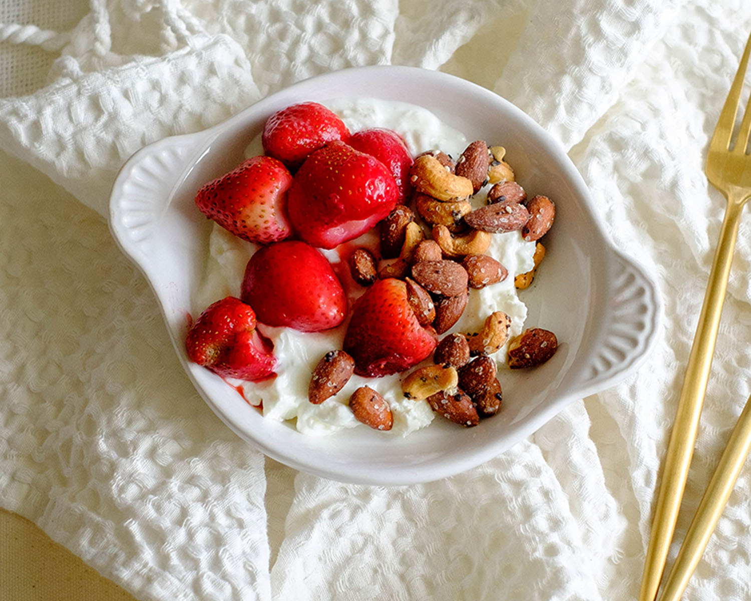 round bowl with yogurt topped with strawberries and mixed nuts for a healthy breakfast