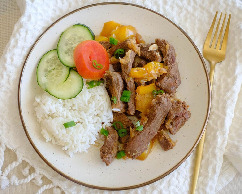 round plate with instant pot beef teriyaki stew, white rice, cucumber, and sliced tomato