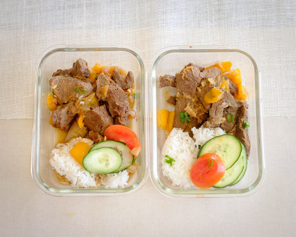 rectangle glass meal prep containers with instant pot beef teriyaki stew, white rice, cucumber, and sliced tomato