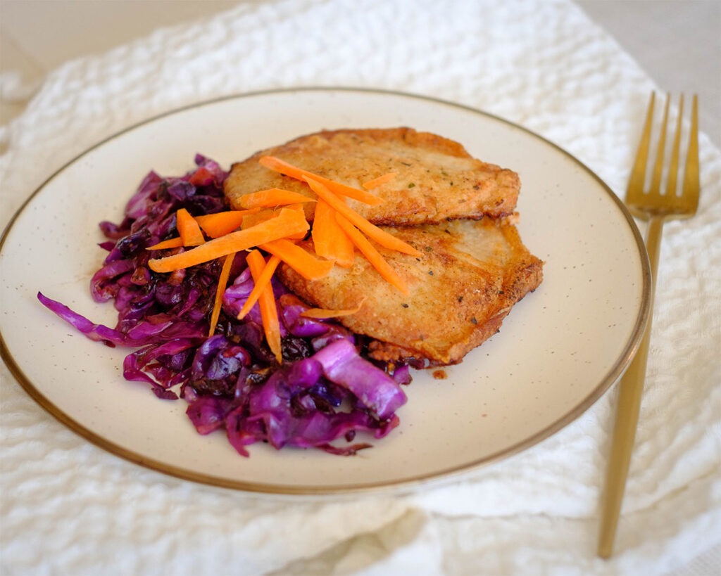 round plate with pork meal prep with sauteed red cabbage
