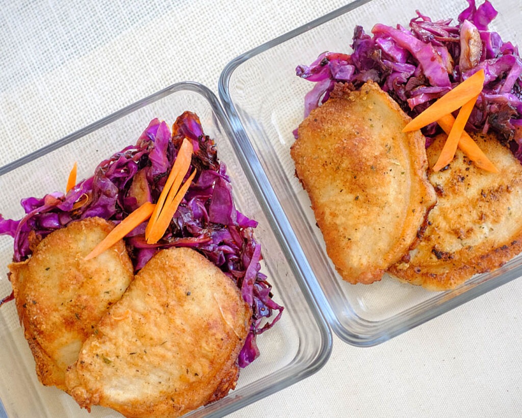 square glass pork meal prep containers with pork chops and sauteed red cabbage