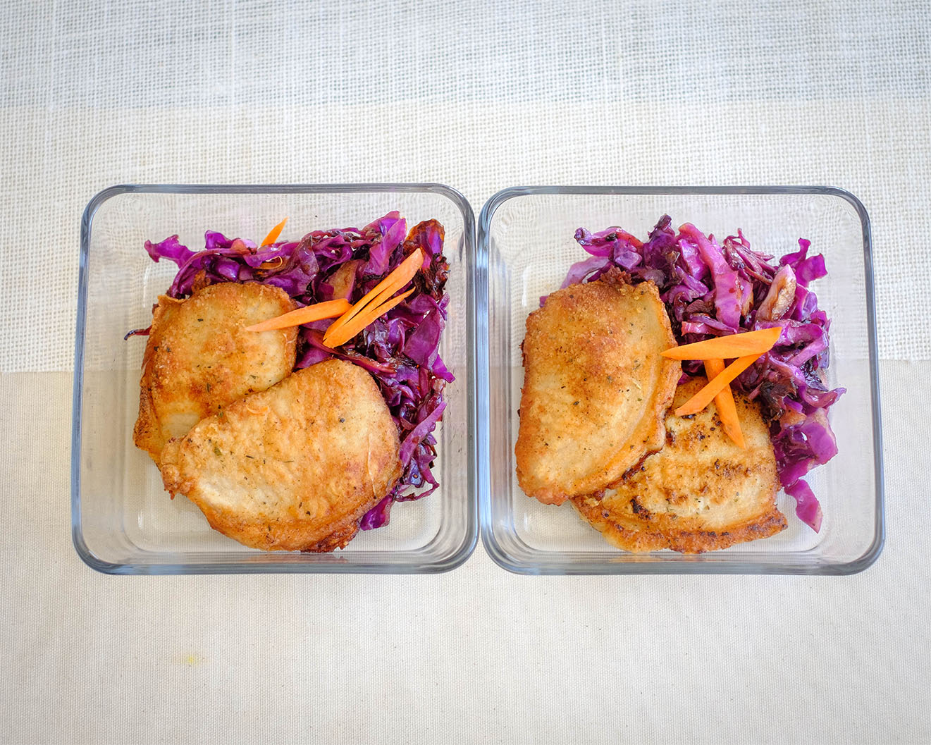 square glass meal prep containers with pork chops and sauteed red cabbage