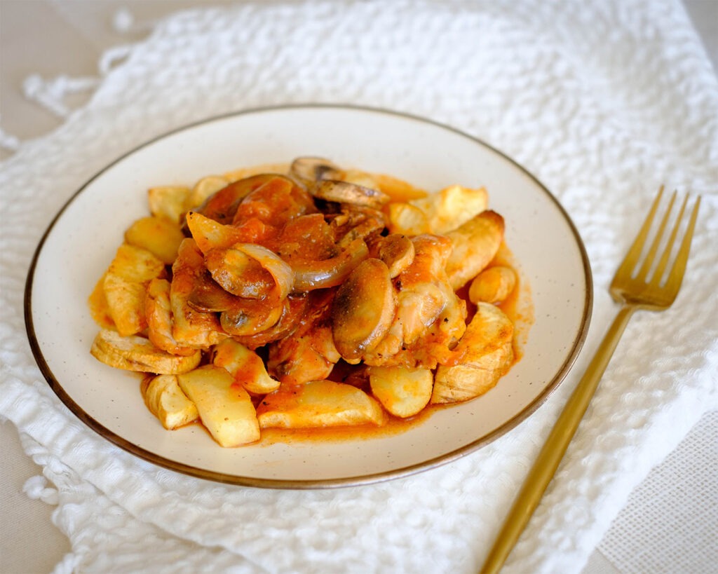 round plate with chicken in tomato sauce with sliced mushrooms and parsnips