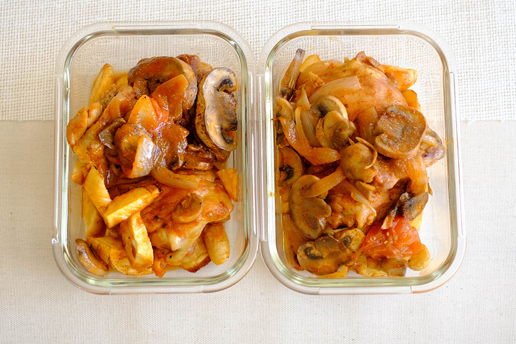 glass meal prep containers with chicken in tomato sauce with sliced mushrooms and parsnips