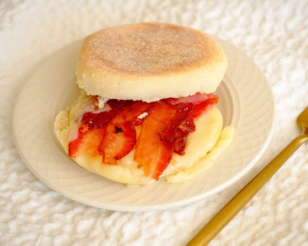 round plate with english muffins, bacon slices, and sliced cheese for a breakfast meal prep