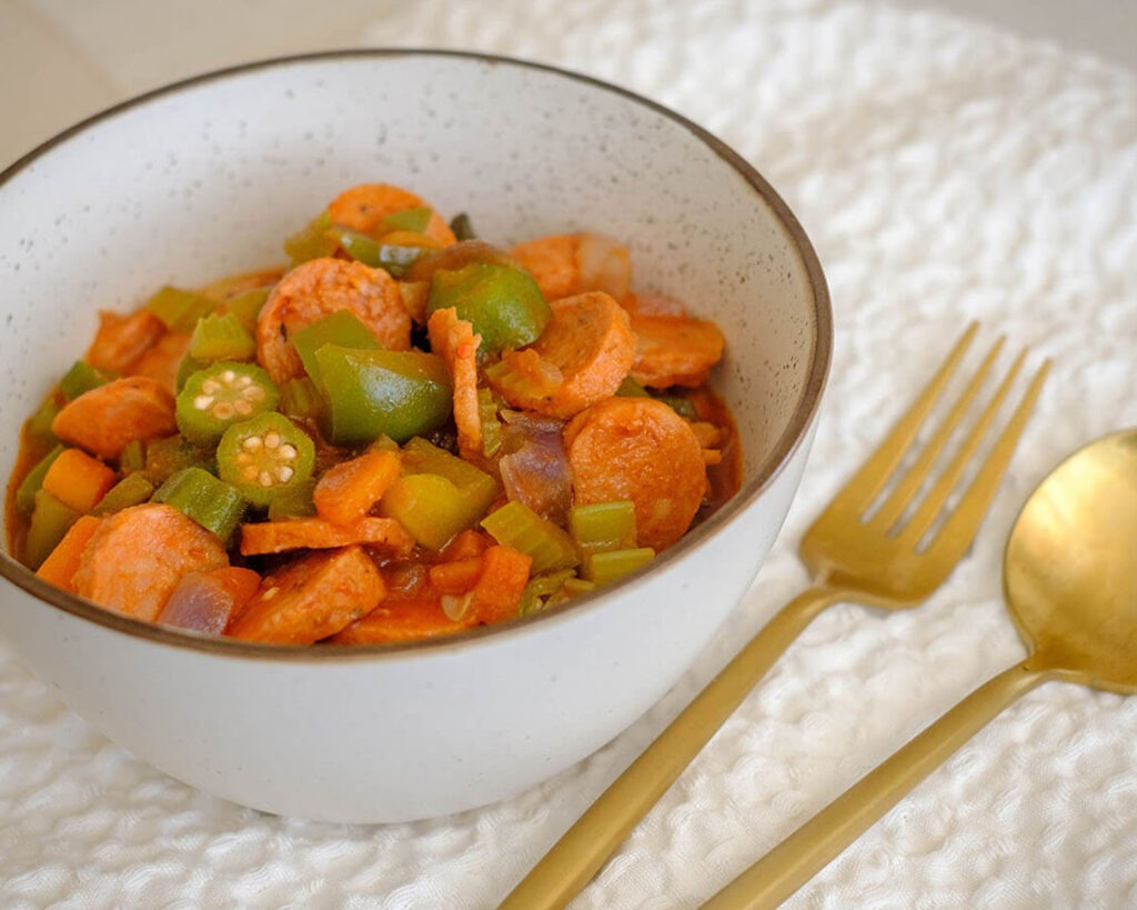 round bowl with cajun sausage stew in tomato sauce with okra and green bell peppers