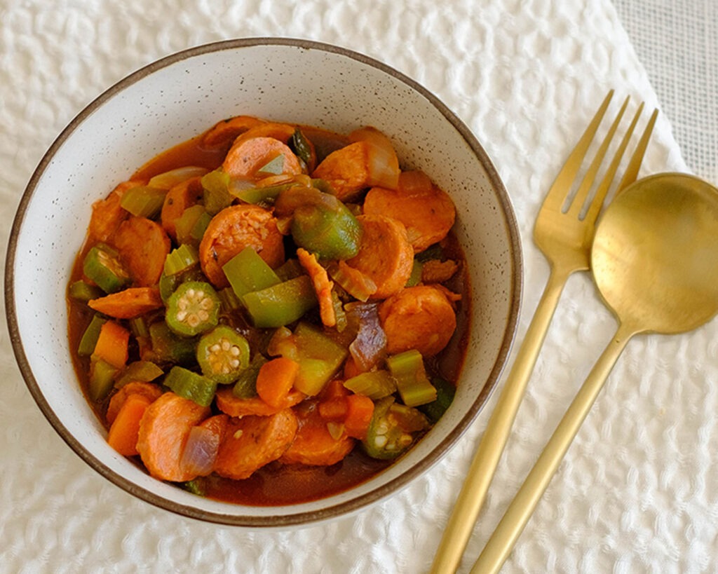 round bowl with cajun sausage stew in tomato sauce with okra and green bell peppers