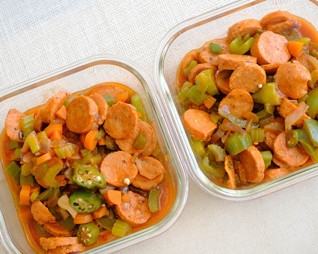 square glass meal prep containers with cajun sausage stew in tomato sauce with okra and green bell peppers