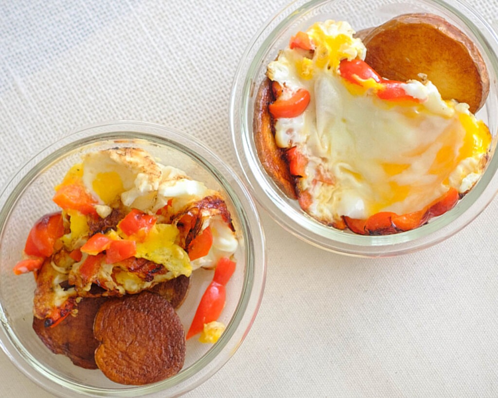 round glass meal prep containers with crispy pan-fried potatoes and fried egg with diced bell peppers