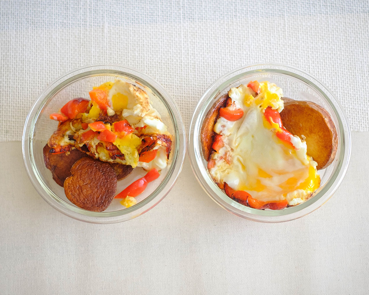 round glass meal prep containers with crispy pan-fried potatoes and fried egg with diced bell peppers