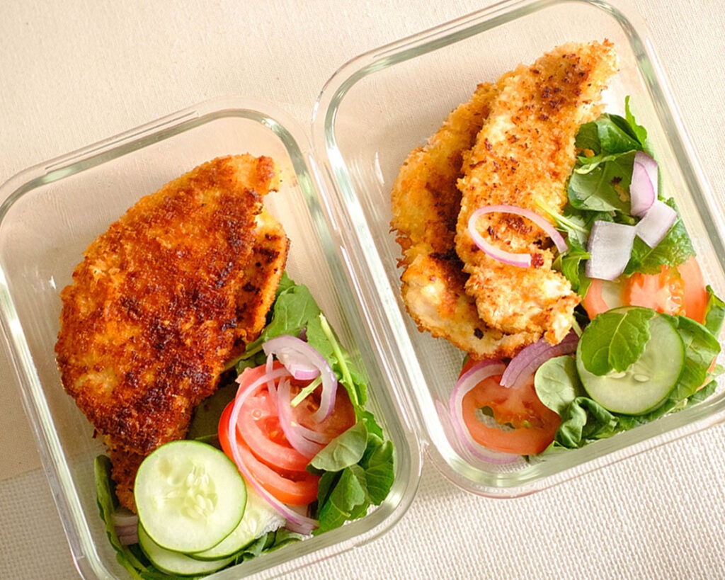 crispy panko breaded chicken tender with salad, sliced cucumbers, tomatoes, and red onions