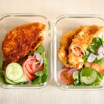 crispy panko breaded chicken tender with salad, sliced cucumbers, tomatoes, and red onions