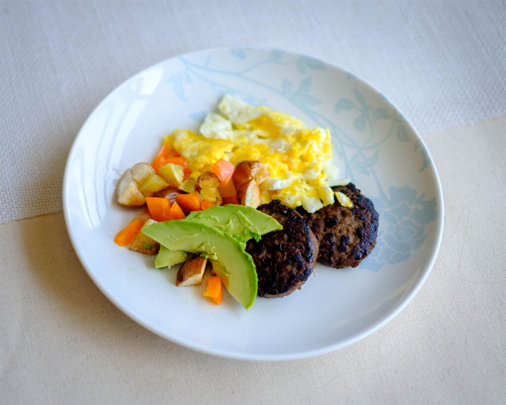 Turkey Sausage Patties with scrambled eggs, diced potatoes and bell peppers, and sliced avocado