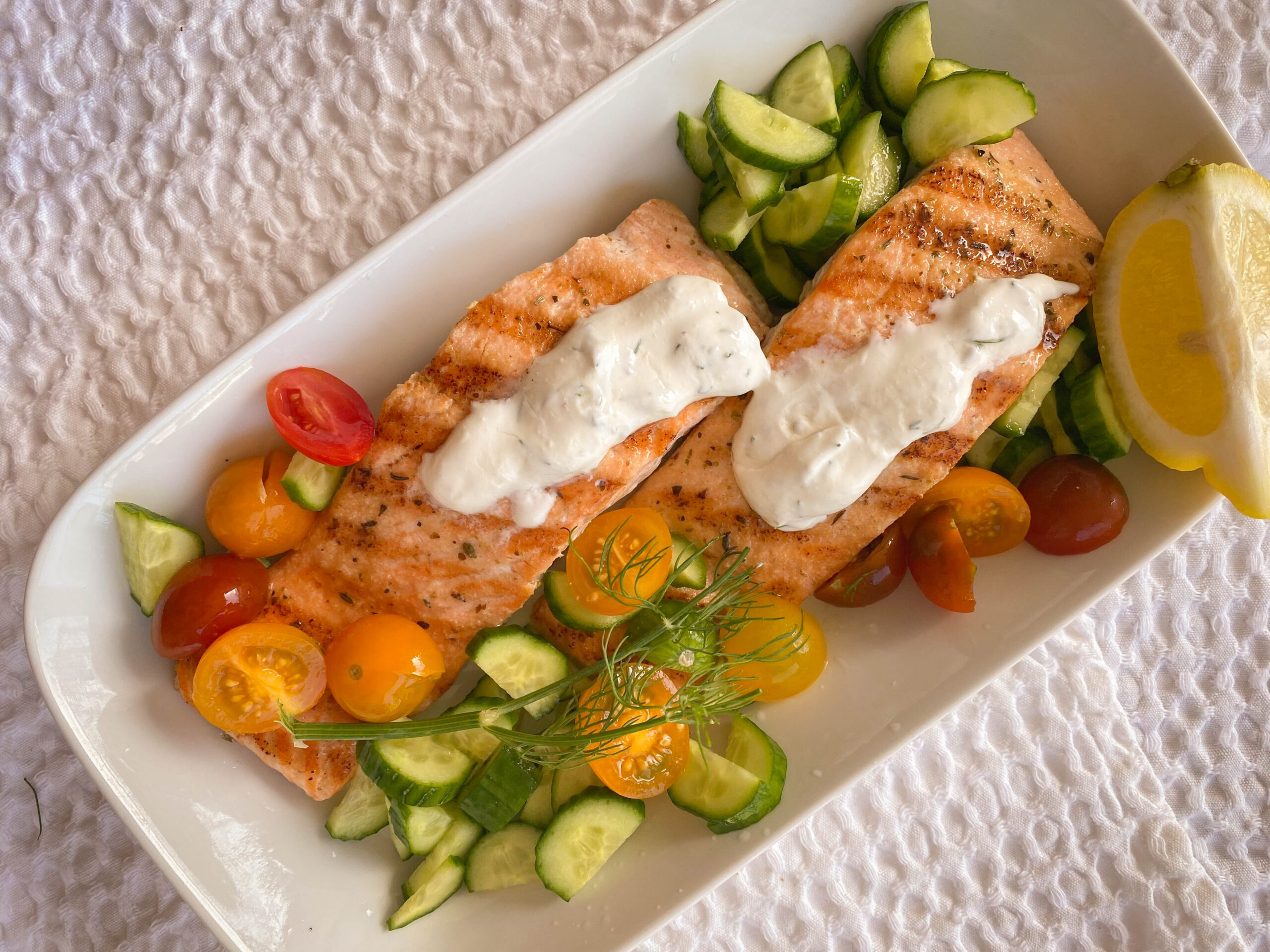 grilled salmon with dill sauce, cherry tomatoes, and cucumbers