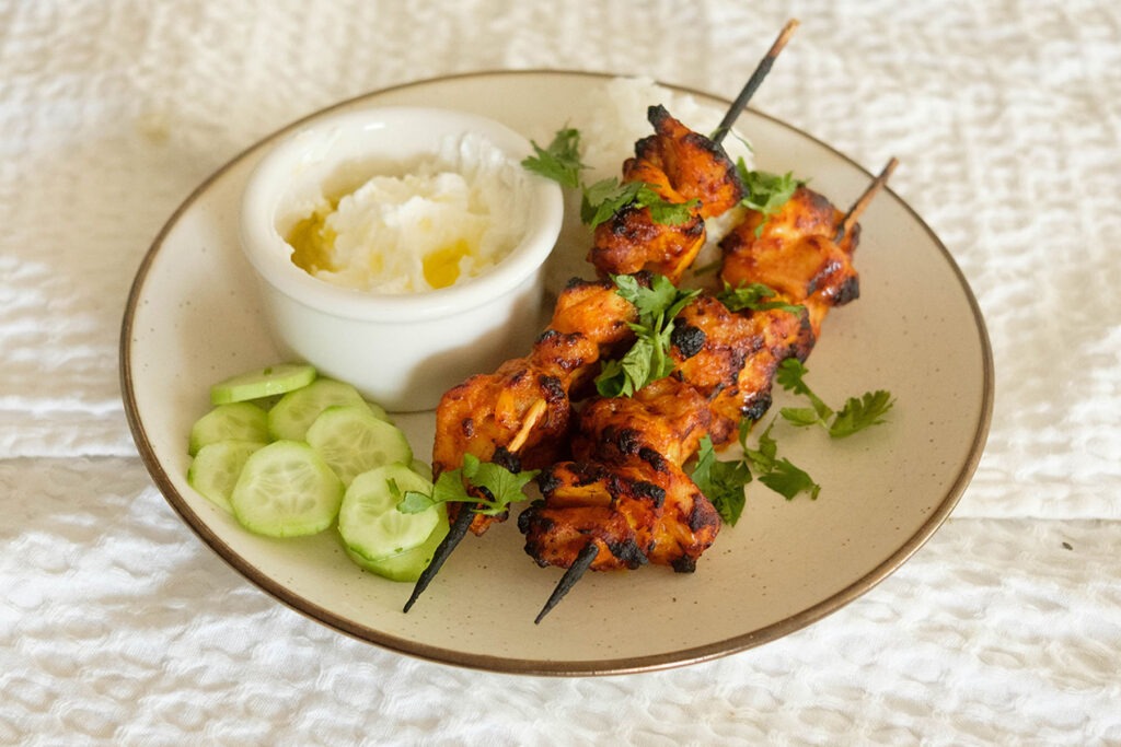 Air Fryer Chicken Curry Skewers with rice, cucumbers, and yogurt sauce.