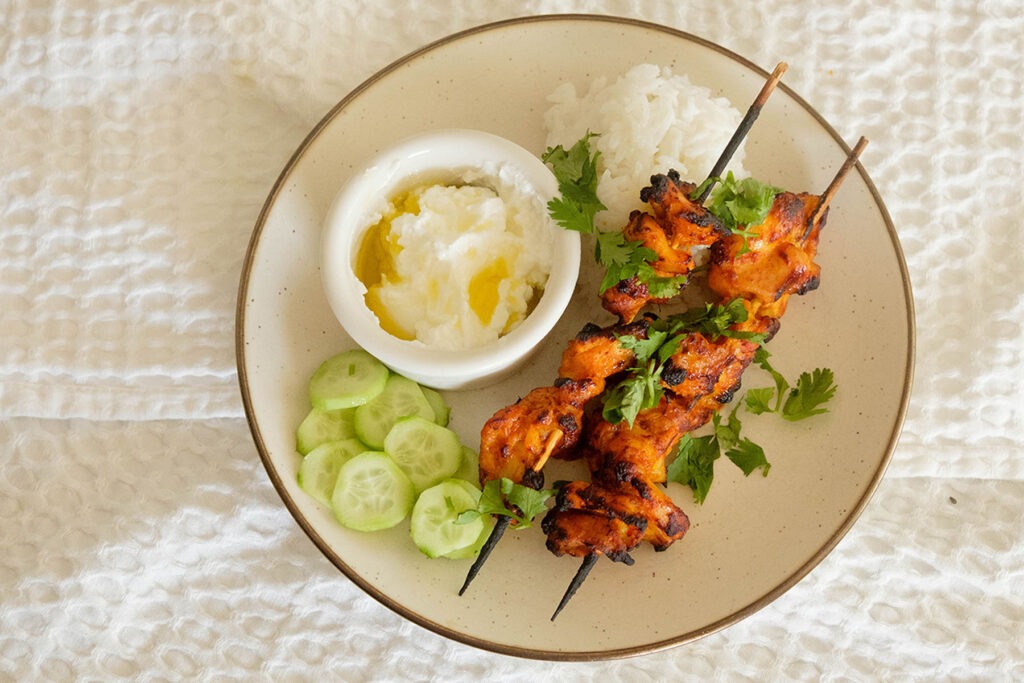 Air Fryer Chicken Curry Skewers with rice, cucumbers, and yogurt sauce.