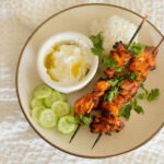 Air Fryer Chicken Curry Skewers with rice, cucumbers, and yogurt sauce.