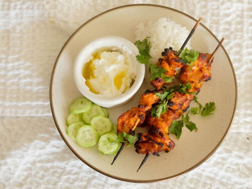 Air Fryer Chicken Curry Skewers with rice, cucumbers, and yogurt sauce.