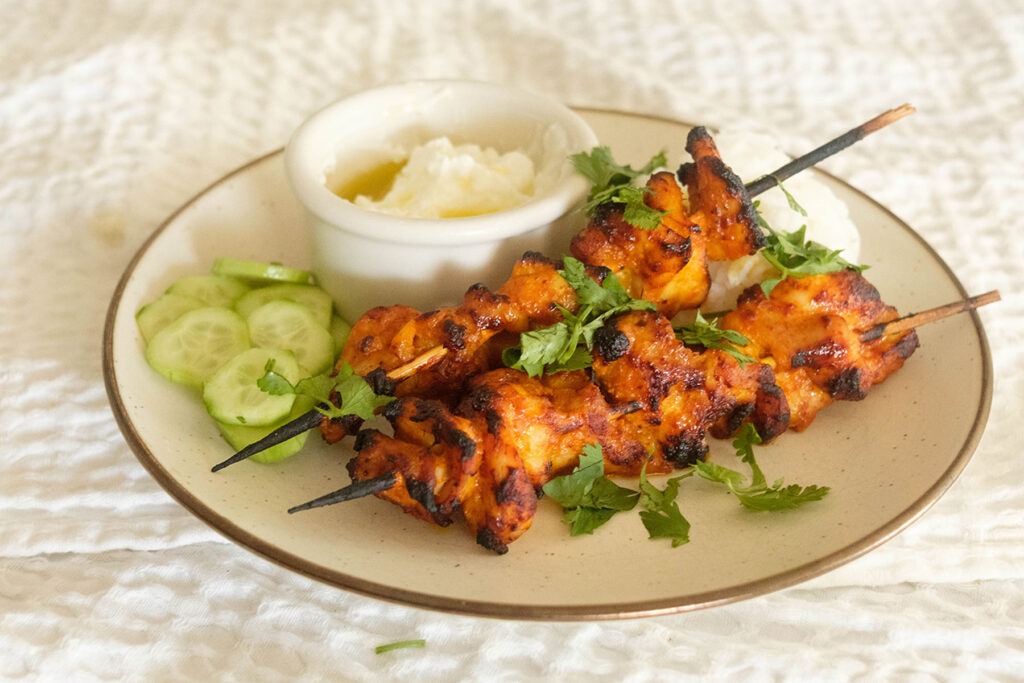 Air Fryer Chicken Curry Skewers with rice, cucumbers, and yogurt sauce.